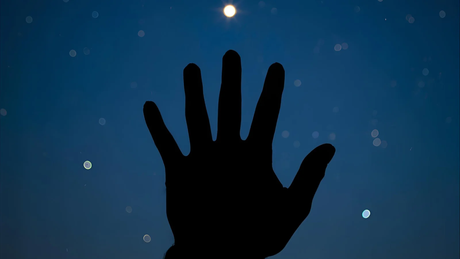 Night sky star and dreamy bokeh light background, silhouette hand reaching for a glowing star, symbolizing a wish.